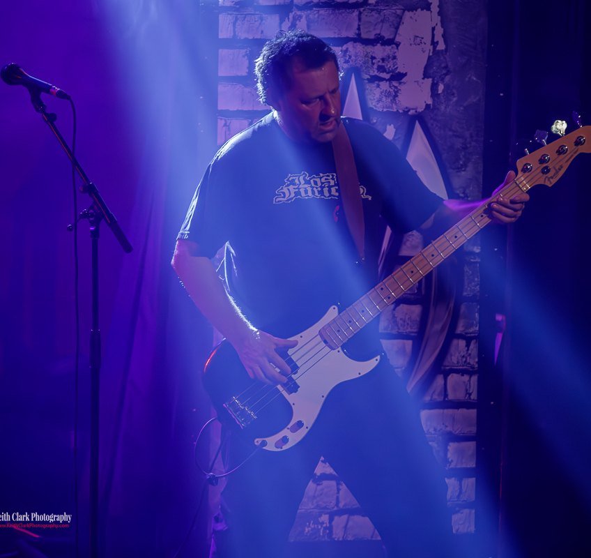 Stuart Hall locked into a bassline, cut out of the dark by a shaft of blue light